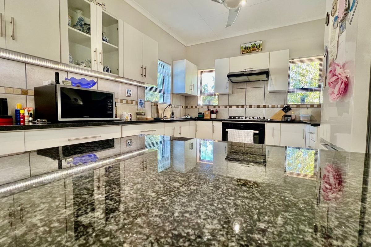 Modern kitchen featuring granite countertops, ample built-in cabinetry, integrated gas hob, oven, and extractor fan with stylish under-cabinet lighting.