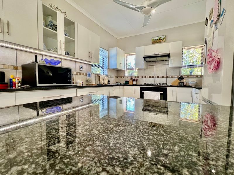 Modern kitchen featuring granite countertops, ample built-in cabinetry, integrated gas hob, oven, and extractor fan with stylish under-cabinet lighting.