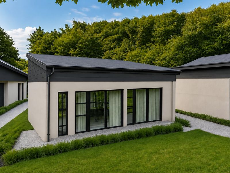 Modern detached structure featuring a mono-pitch roof, black framed sliding glass doors, and well-maintained surrounding gravel pathways and lawn.