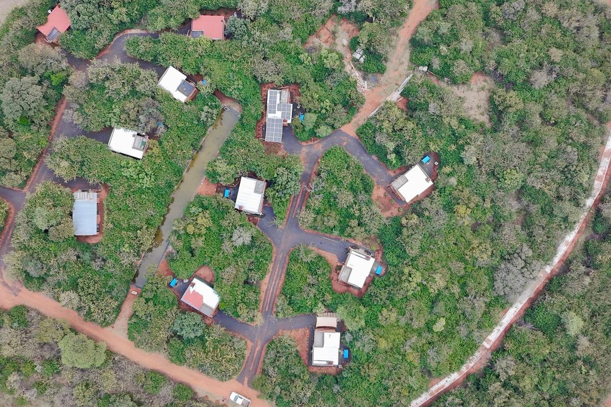 Aerial view of a lodge property featuring multiple detached units, paved access roads, and integrated solar panel installations set within a natural landscape.