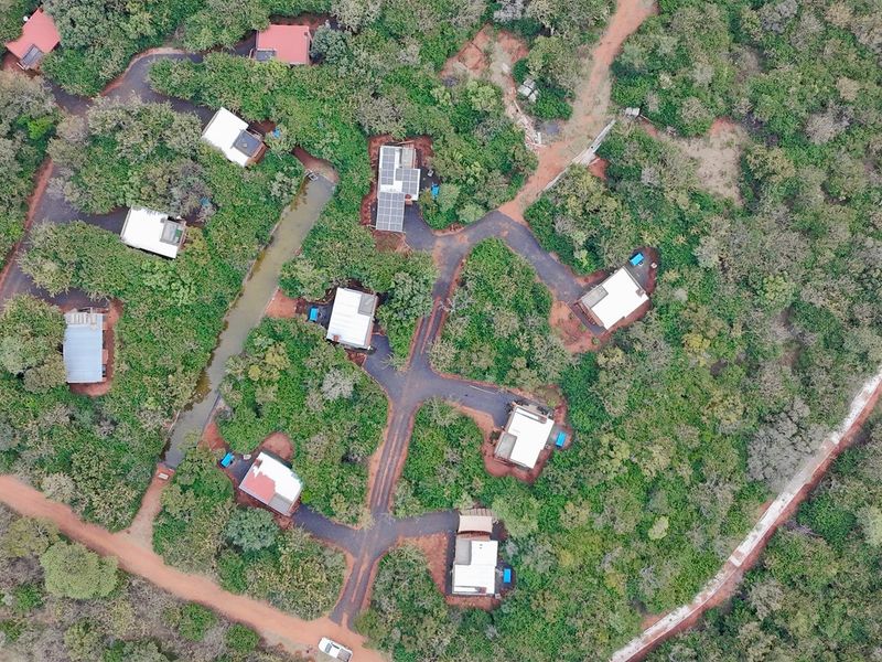 Aerial view of a lodge property featuring multiple detached units, paved access roads, and integrated solar panel installations set within a natural landscape.