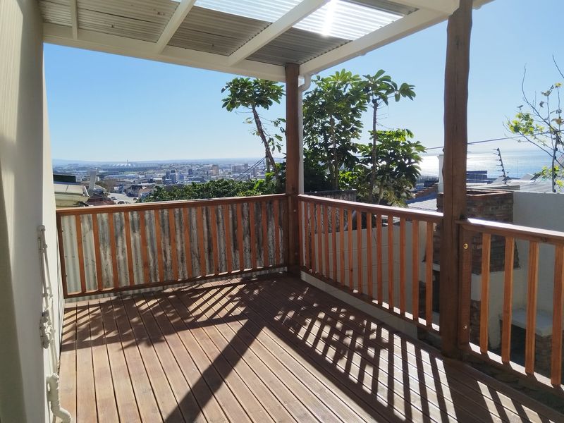 Covered timber balcony featuring a built-in brick braai and expansive city and ocean views.