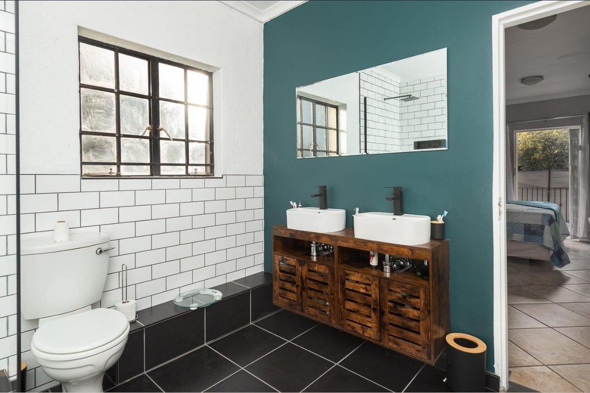 A modern bathroom featuring a double vanity with vessel sinks, black fixtures, subway tile backsplash, and dark floor tiling.