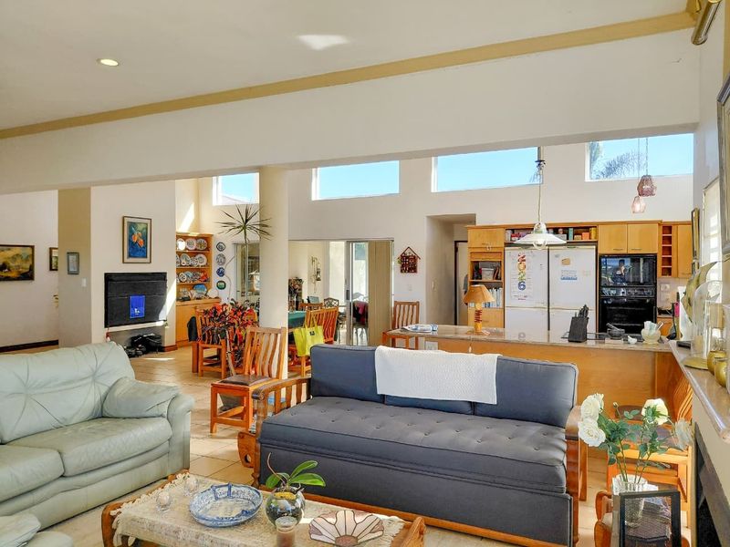 Spacious open-plan living and kitchen area featuring high ceilings, clerestory windows for natural light, tiled flooring, and a functional kitchen island layout.