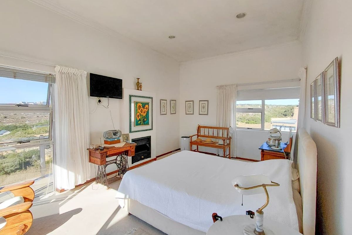 Spacious bedroom featuring a built-in fireplace, recessed lighting, and large windows with scenic views, offering a bright and airy atmosphere.