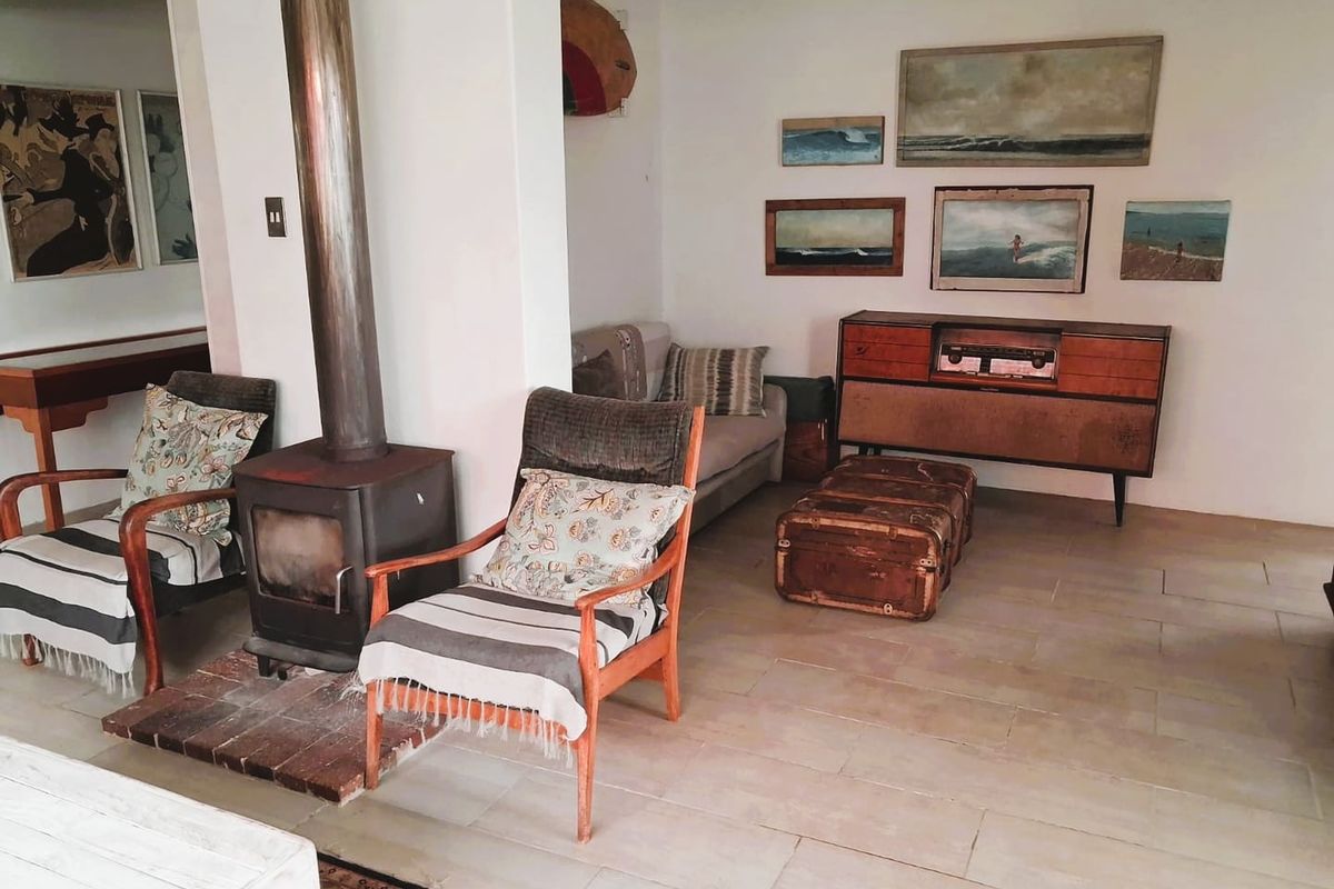 A living room featuring a freestanding fireplace with a flue pipe and neutral tiled flooring, offering a cozy and rustic atmosphere.
