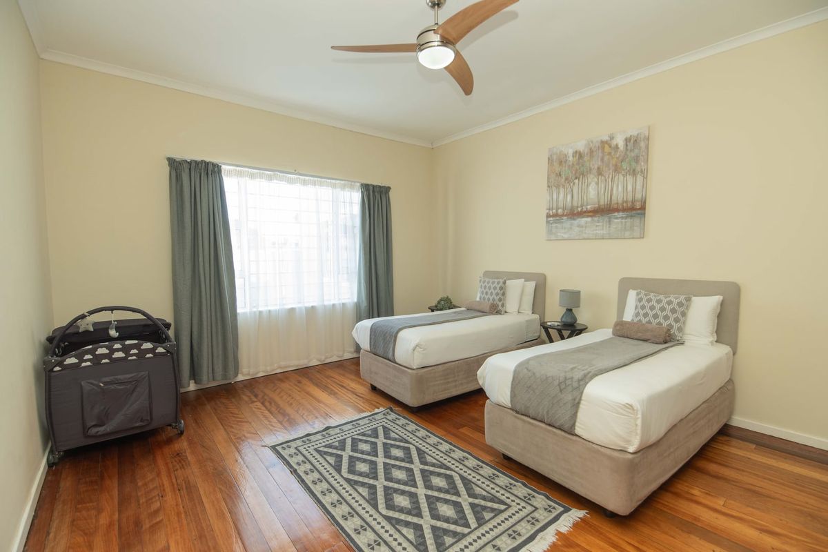 A spacious bedroom featuring polished hardwood flooring, neutral wall tones, and a modern ceiling fan, offering a comfortable and well-maintained living space.