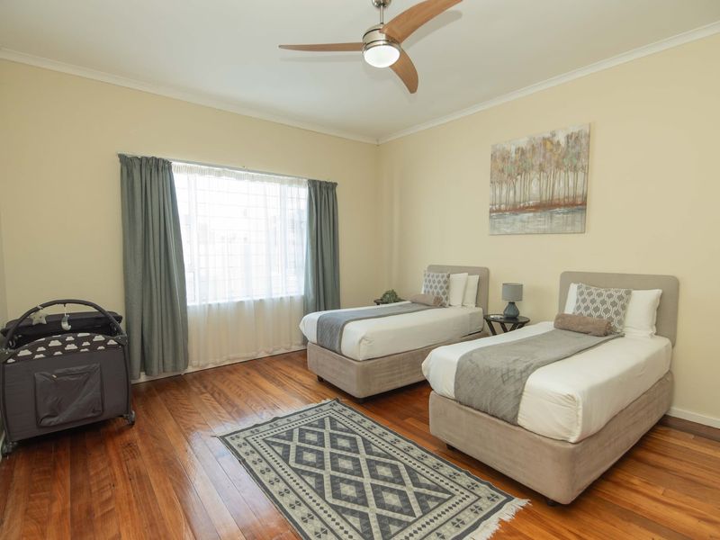 A spacious bedroom featuring polished hardwood flooring, neutral wall tones, and a modern ceiling fan, offering a comfortable and well-maintained living space.