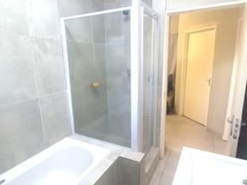 A clean, modern bathroom featuring a separate shower enclosure and bathtub with neutral wall and floor tiling.