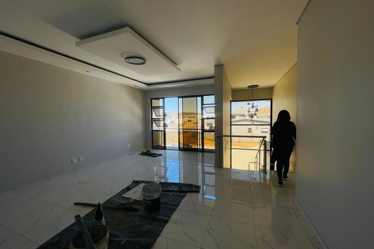 Spacious, modern living area featuring large windows, polished porcelain tiles, and a contemporary recessed ceiling design, currently in the final stages of completion.