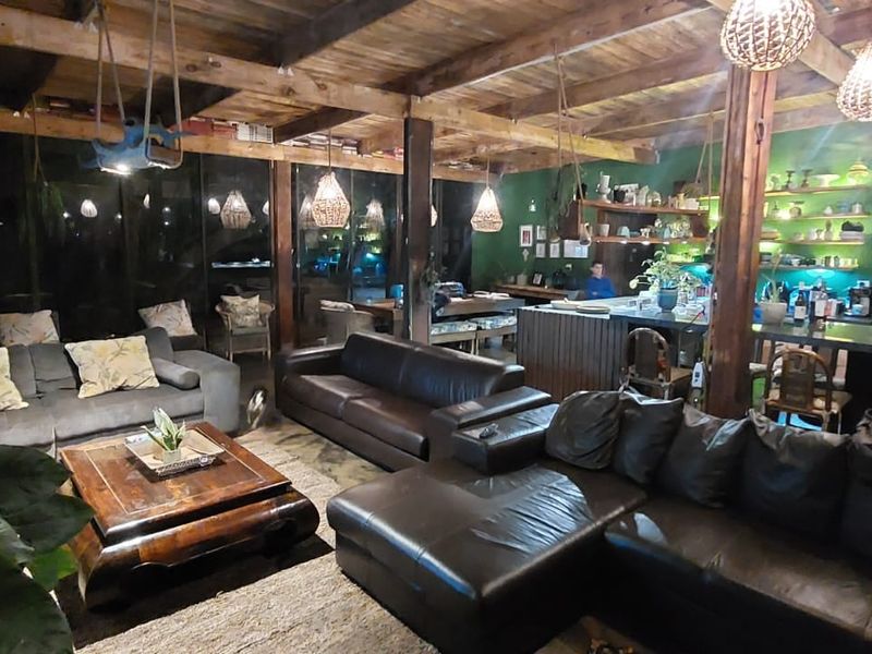 Spacious open-plan living and kitchen area featuring exposed timber ceiling beams, concrete flooring, and a functional kitchen island with open shelving.