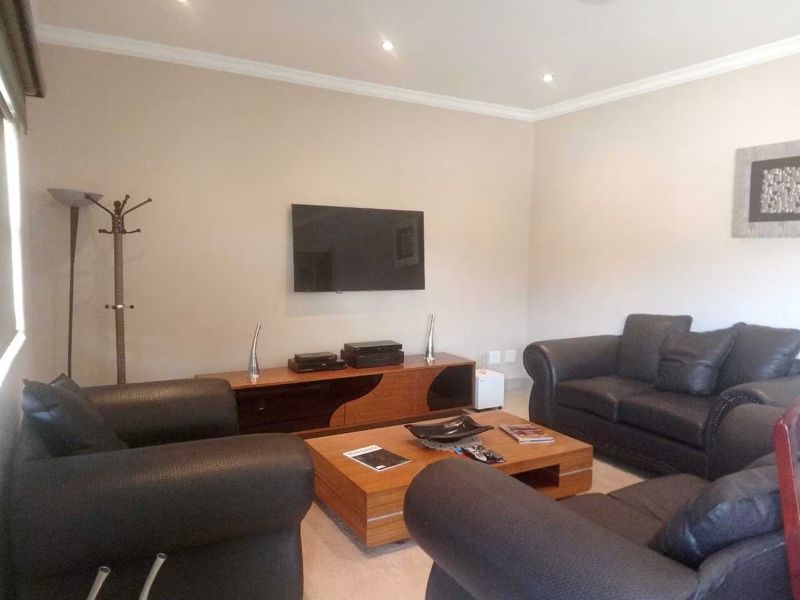 A well-maintained living room featuring recessed downlighting and decorative coving, providing a comfortable and neutral space for relaxation.