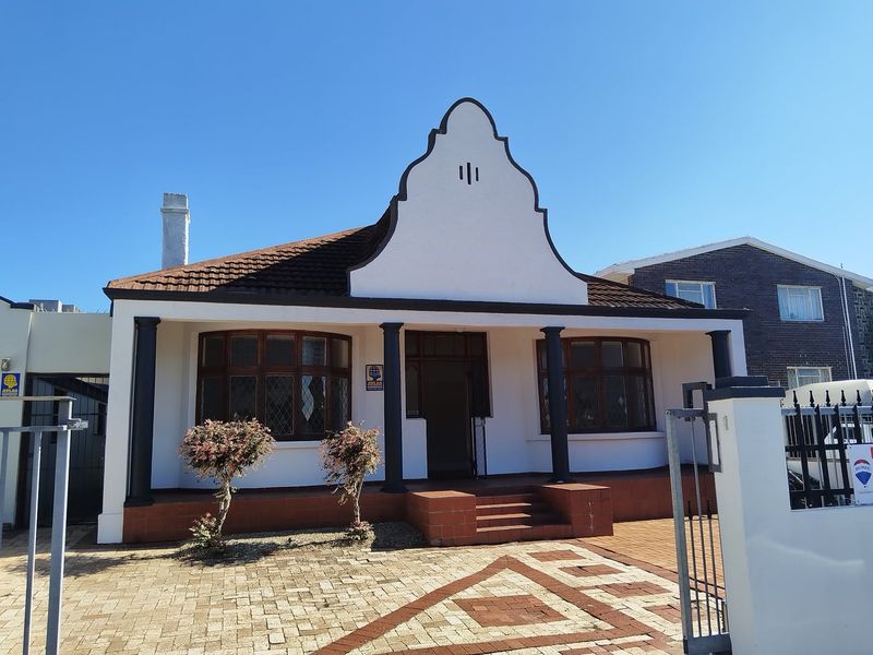 Front elevation of a charming property featuring a distinctive gabled roof, covered porch with columns, and a paved driveway.