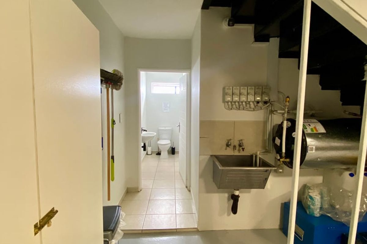Utility area featuring a stainless steel sink, electric water heater, and direct access to a small bathroom with tiled flooring.