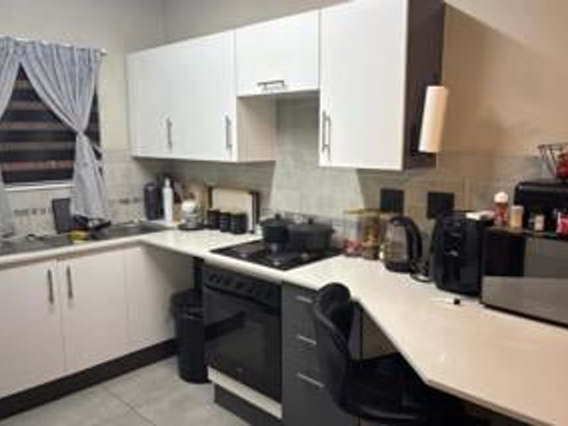 A functional kitchen featuring white cabinetry, dark grey lower units, stone-look countertops, and a built-in electric oven and stove.
