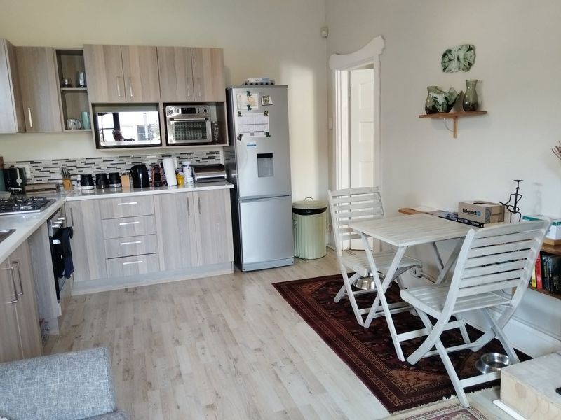 Open-plan kitchen featuring light wood-finish cabinetry, modern appliances, and durable laminate flooring, seamlessly integrated with a casual dining area.