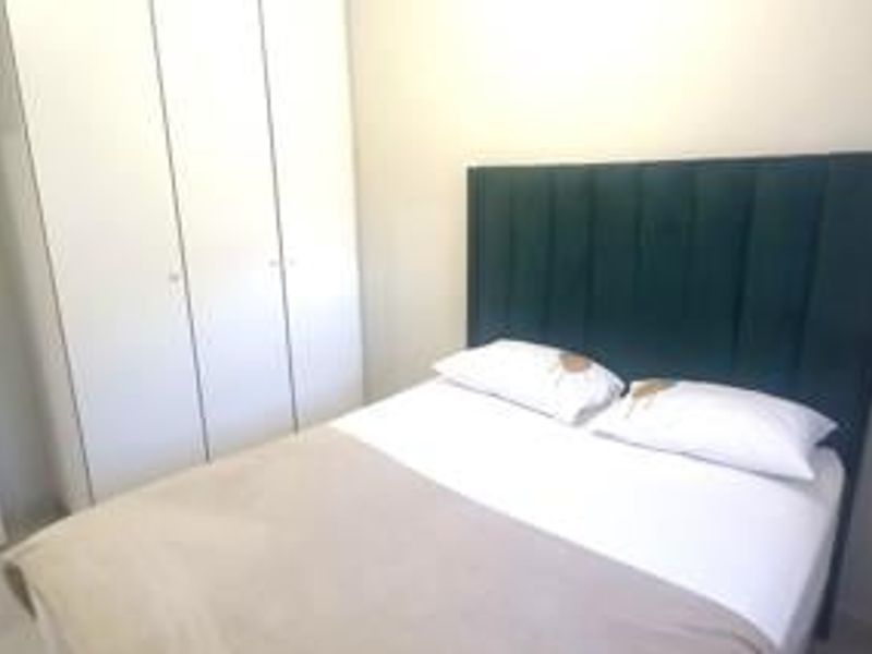 A clean and functional bedroom featuring a built-in wardrobe with white cabinetry.