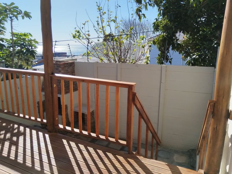 Outdoor wooden deck featuring a built-in brick braai, wooden balustrade, and views of the surrounding area.