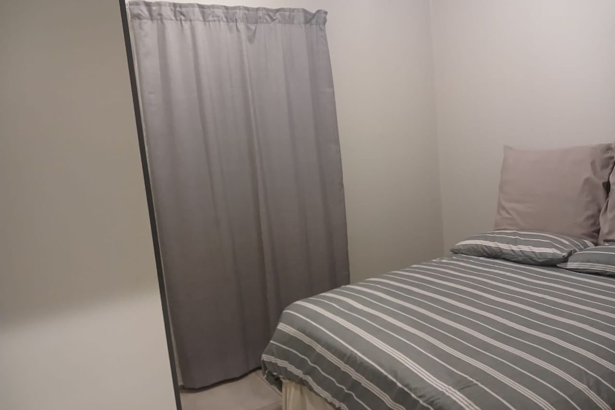 A simple bedroom featuring neutral walls and a built-in cupboard, providing a functional and clean living space.
