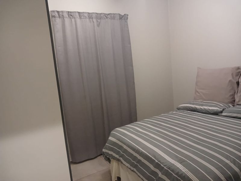 A simple bedroom featuring neutral walls and a built-in cupboard, providing a functional and clean living space.