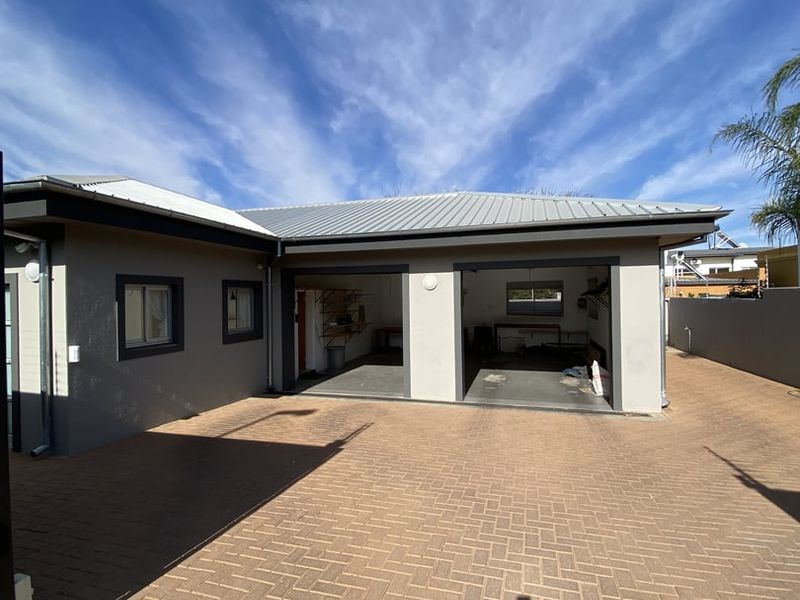 A well-maintained double garage with a paved driveway and modern exterior finishes under a metal roof.