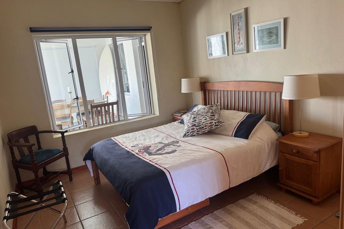 A comfortable bedroom featuring tiled flooring and a large window that allows for natural light, creating a bright and inviting atmosphere.