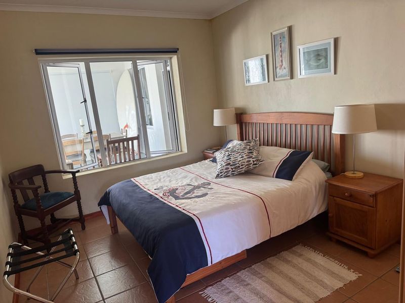 A comfortable bedroom featuring tiled flooring and a large window that allows for natural light, creating a bright and inviting atmosphere.