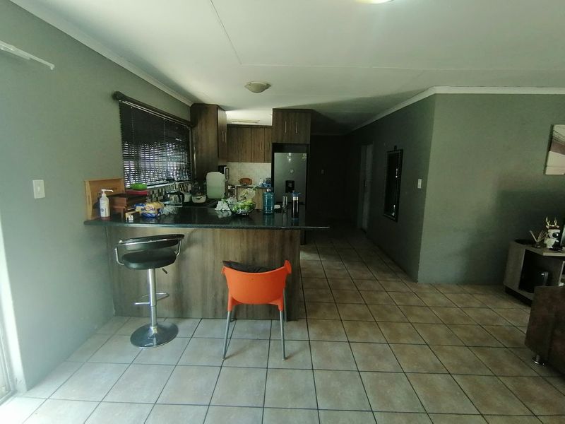 Open plan living area featuring a kitchen with built-in cabinetry, granite countertops, and a breakfast bar, finished with tiled flooring throughout.