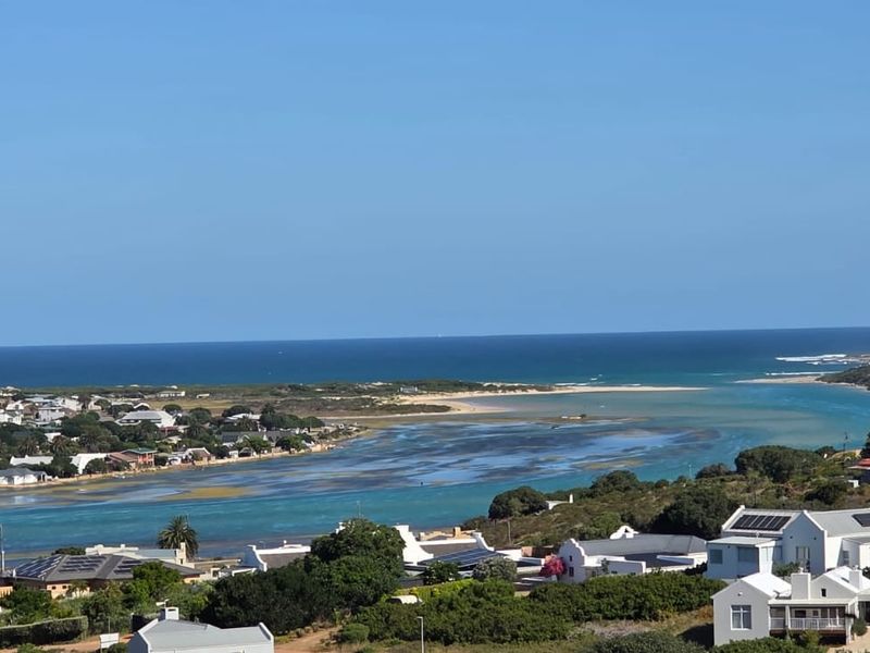 A scenic elevated view overlooking a coastal estuary, surrounding residential properties, and the distant ocean horizon.