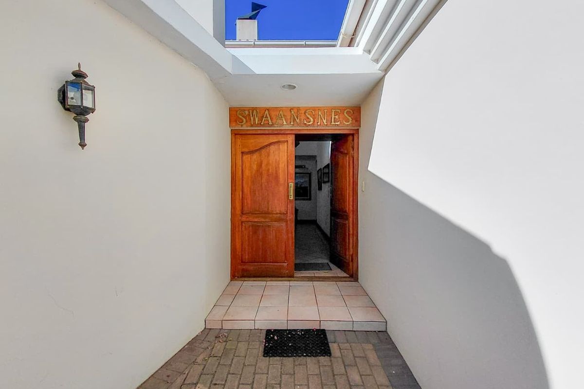 A welcoming front entrance featuring a solid wooden double door, paved walkway, and a tiled step leading into the home.
