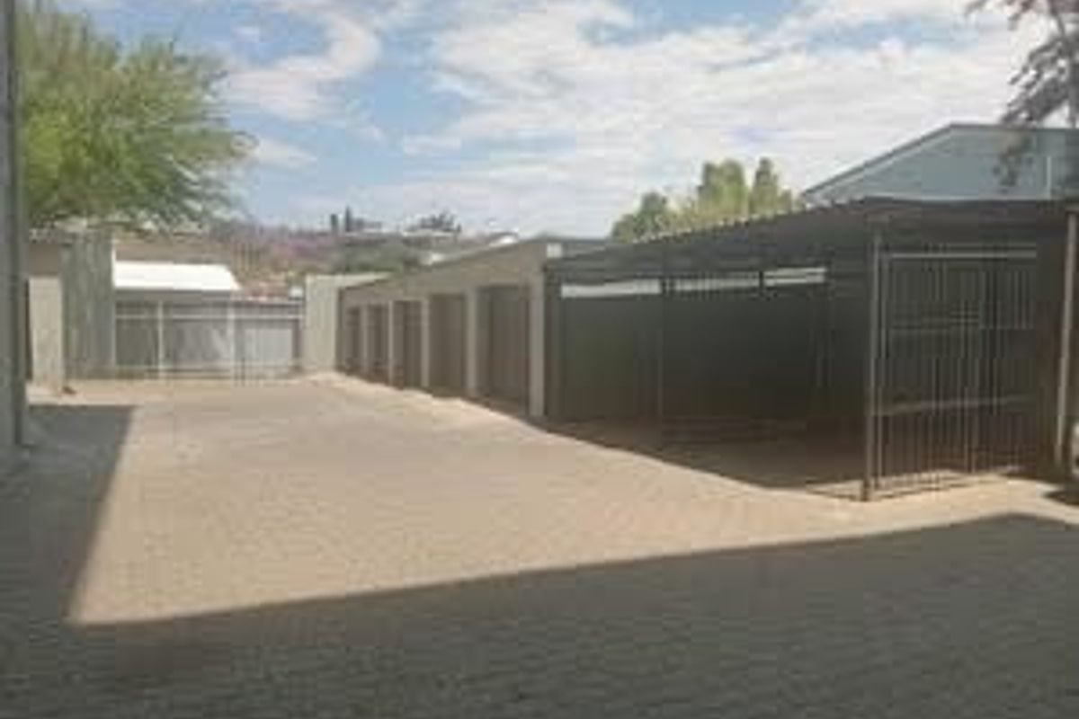 Exterior view of the apartment complex parking area featuring paved driveway, multiple garage units, and a covered carport structure.