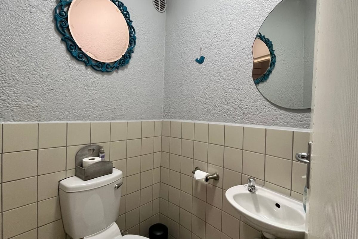 A compact guest cloakroom featuring a wall-mounted basin, a standard toilet, and half-tiled walls with textured upper wall finishes.