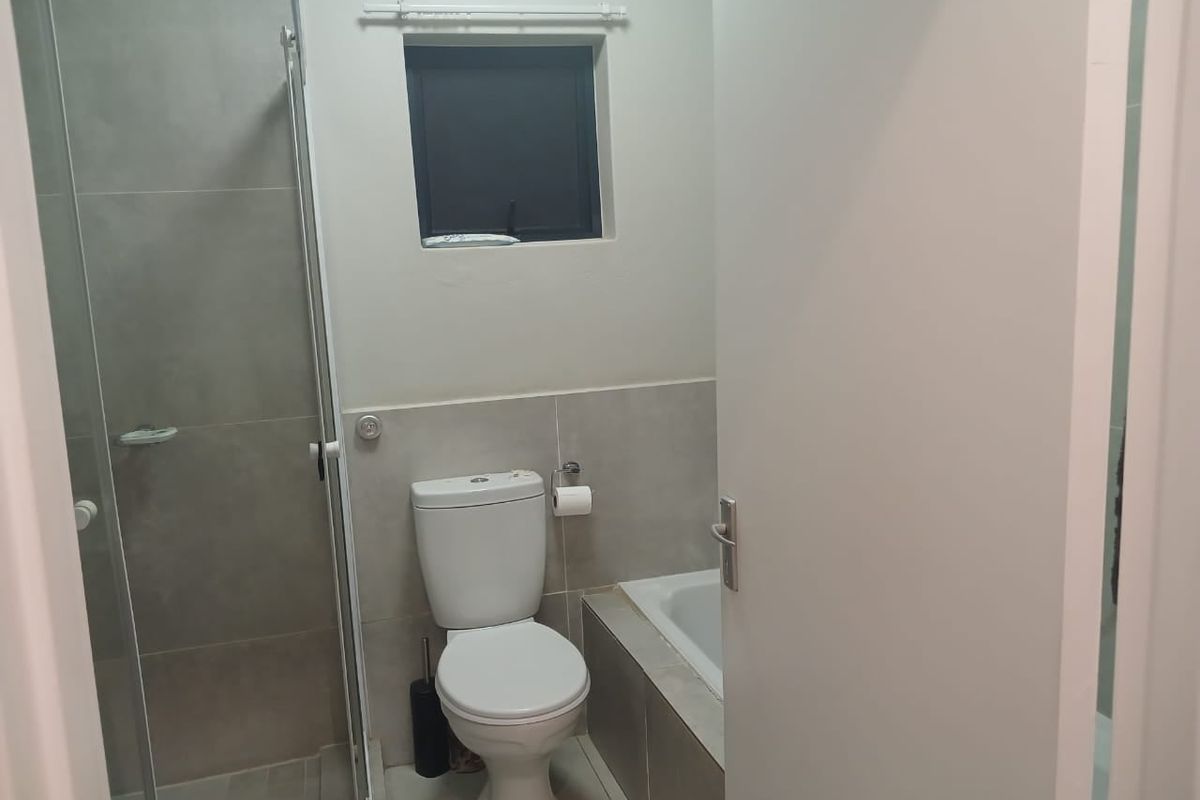 A clean, functional bathroom featuring a separate shower enclosure, a bathtub, and neutral wall tiling.