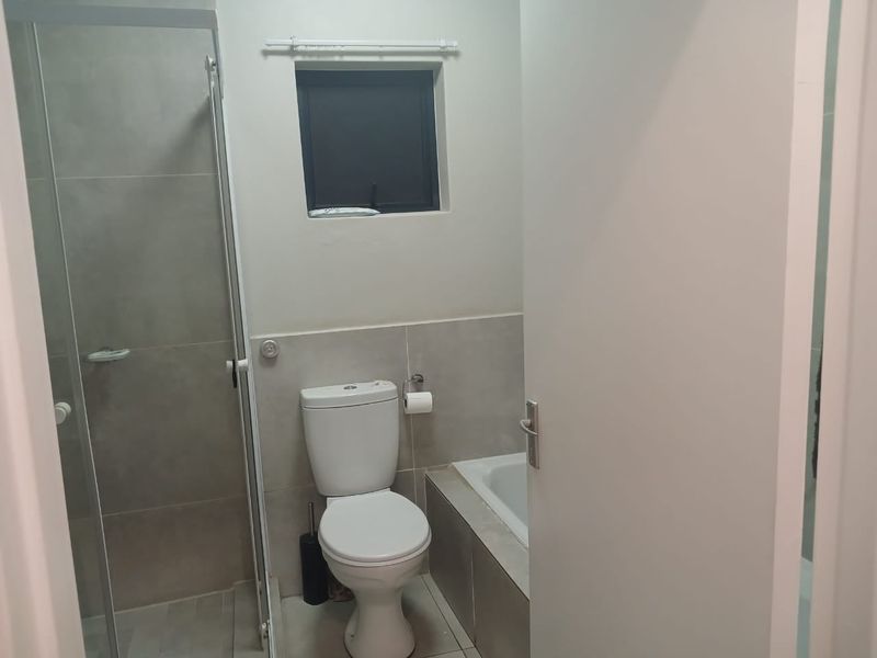 A clean, functional bathroom featuring a separate shower enclosure, a bathtub, and neutral wall tiling.