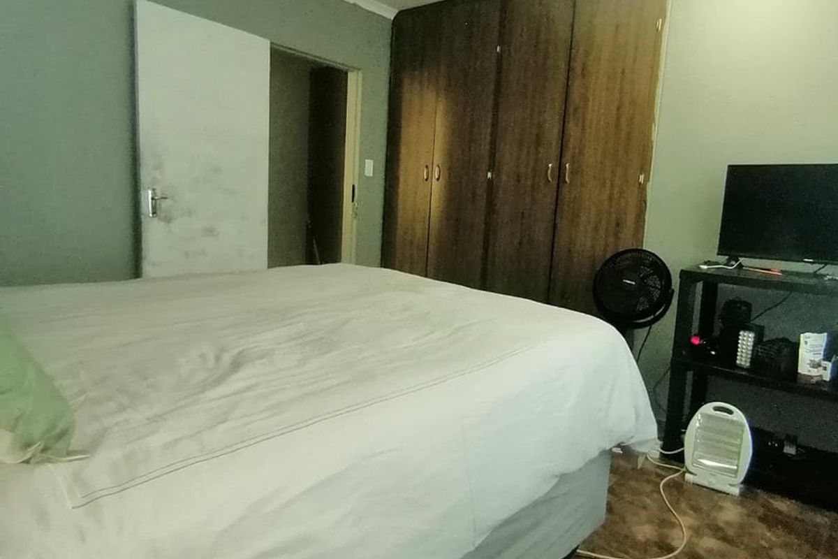 A bedroom featuring built-in wooden cupboards and tiled flooring, requiring minor cosmetic updates to improve the overall aesthetic.