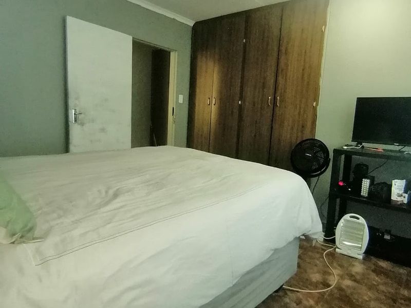 A bedroom featuring built-in wooden cupboards and tiled flooring, requiring minor cosmetic updates to improve the overall aesthetic.