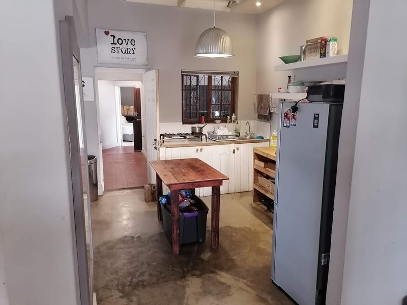 A functional kitchen space featuring a gas hob, stainless steel sink, built-in cabinetry, and concrete flooring, offering potential for modernization and aesthetic improvement.