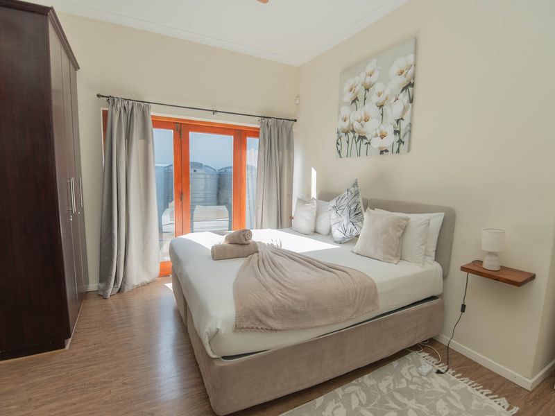 A well-maintained bedroom featuring laminate flooring, a built-in wardrobe, and double glass doors providing access to the exterior.
