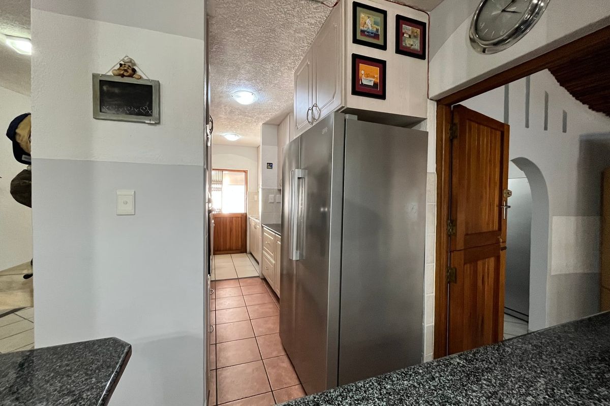A view into a functional kitchen area featuring tiled flooring, built-in cabinetry, and a stainless steel refrigerator.