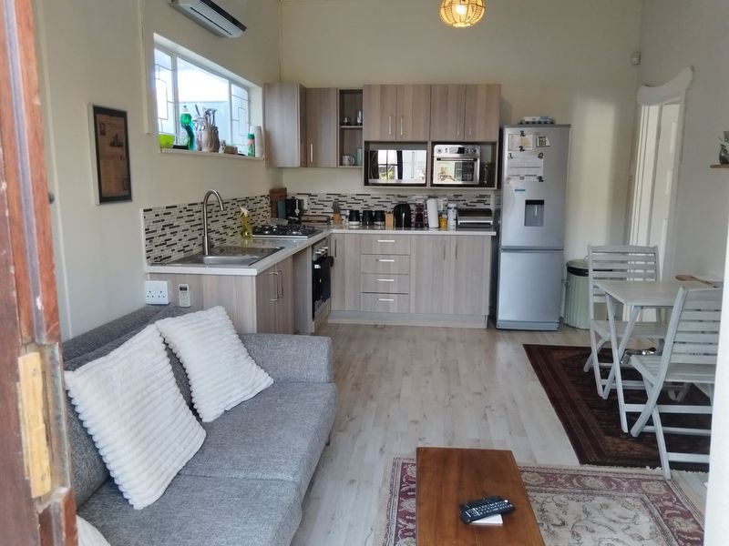 Open-plan living area featuring a modern kitchen with built-in cabinetry, integrated appliances, and laminate flooring, seamlessly connecting to the lounge and dining space.