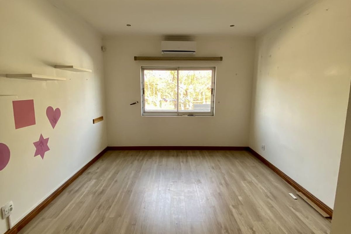 An empty bedroom featuring light-toned laminate flooring, a split-system air conditioner, and recessed lighting, ready for personalization.