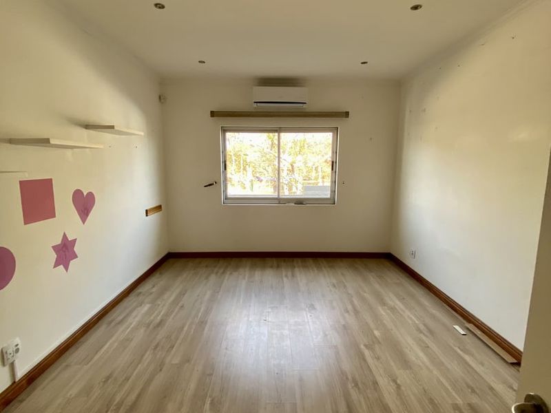An empty bedroom featuring light-toned laminate flooring, a split-system air conditioner, and recessed lighting, ready for personalization.