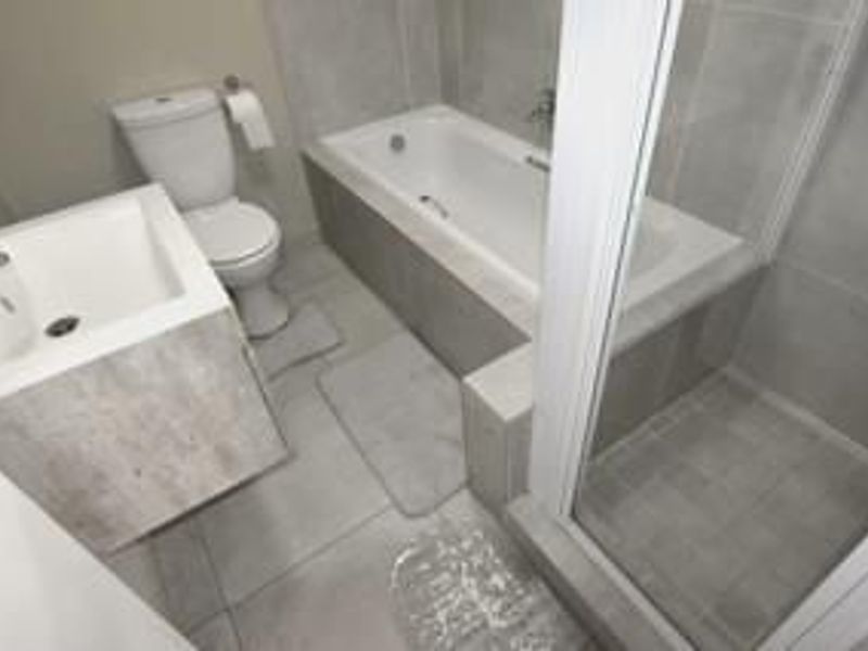 Modern bathroom featuring a built-in bathtub, separate glass-enclosed shower, and a contemporary wall-mounted vanity with neutral tiled finishes.