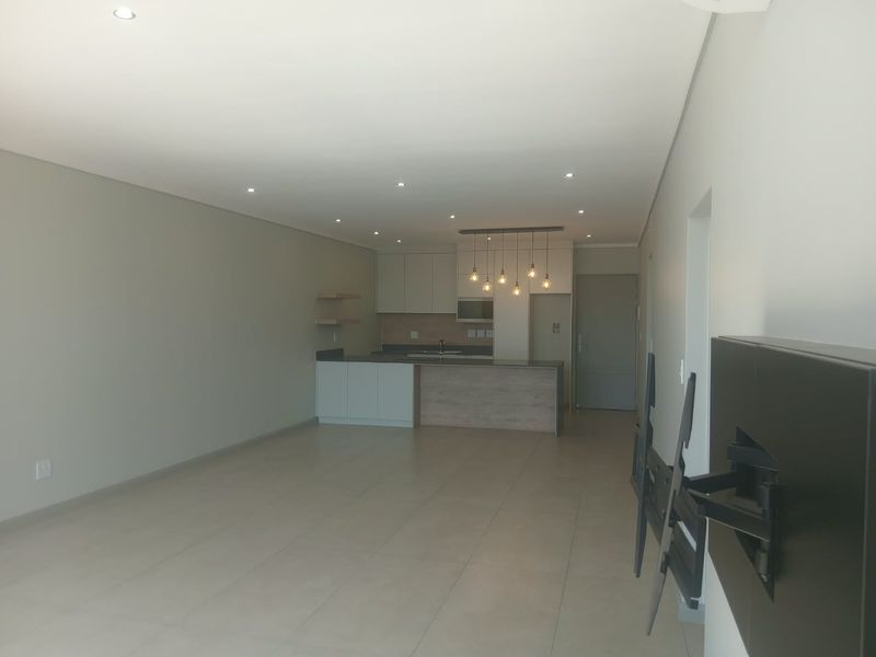 Spacious open-plan living and kitchen area featuring modern cabinetry, a kitchen island, recessed lighting, and neutral tiled flooring throughout.