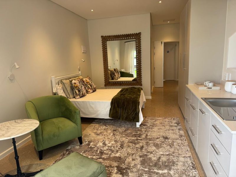 A modern open-plan studio apartment featuring polished concrete floors, built-in cabinetry with stone countertops, and recessed lighting in a well-maintained retirement village setting.