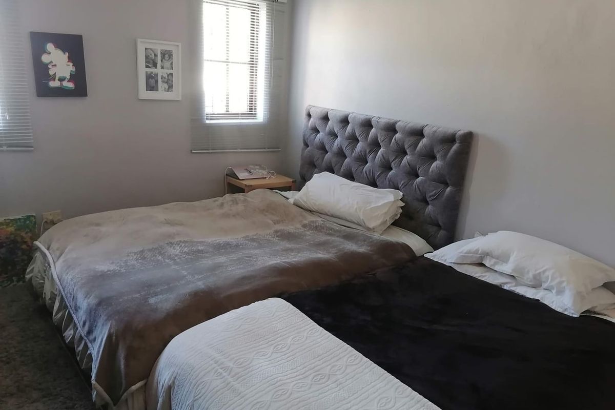 A bedroom featuring neutral wall finishes and venetian blinds, providing a functional space for rest.