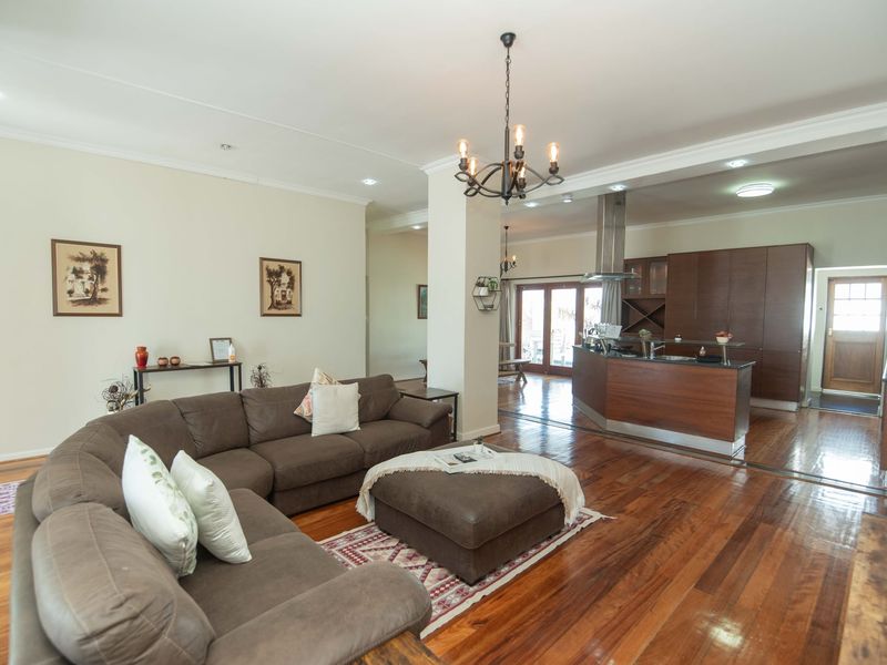 Spacious open-plan living area featuring warm hardwood flooring, a modern kitchen with built-in cabinetry, and a central island, creating a seamless flow for entertaining.
