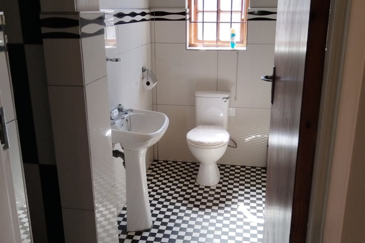 A functional bathroom featuring a pedestal basin, toilet, and classic black and white checkered floor tiling.