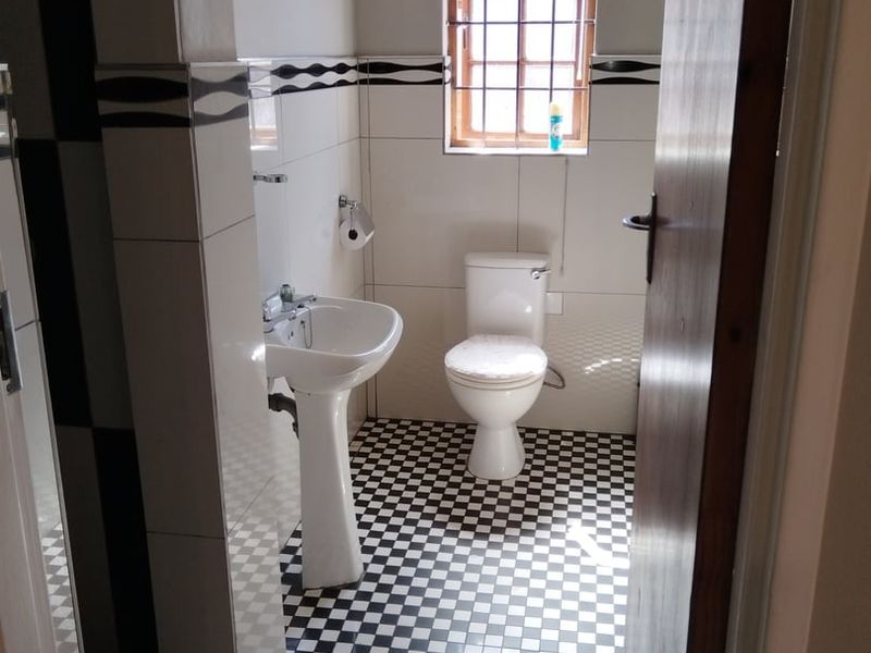 A functional bathroom featuring a pedestal basin, toilet, and classic black and white checkered floor tiling.