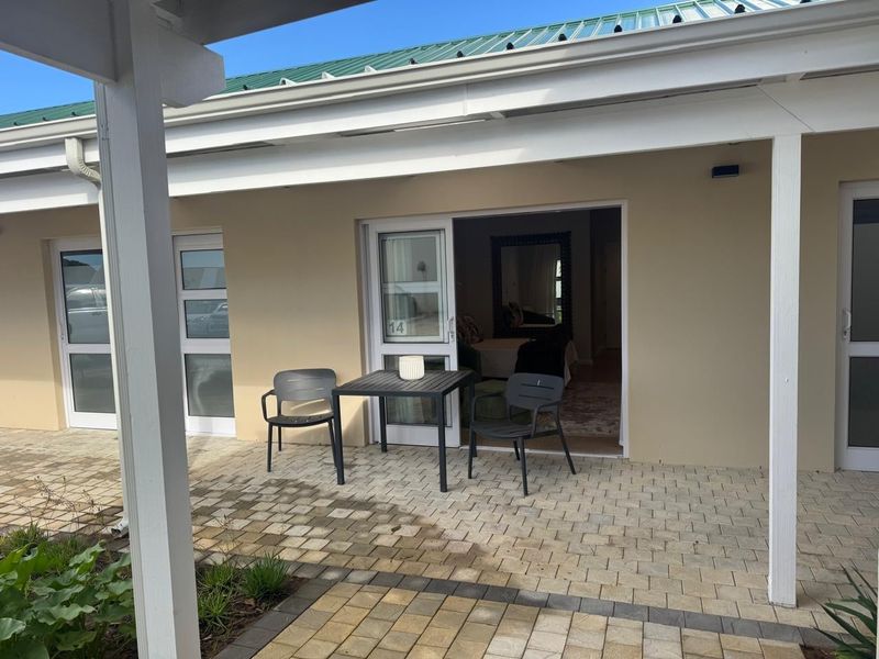A covered patio area featuring paved flooring and sliding glass door access to the interior living space.